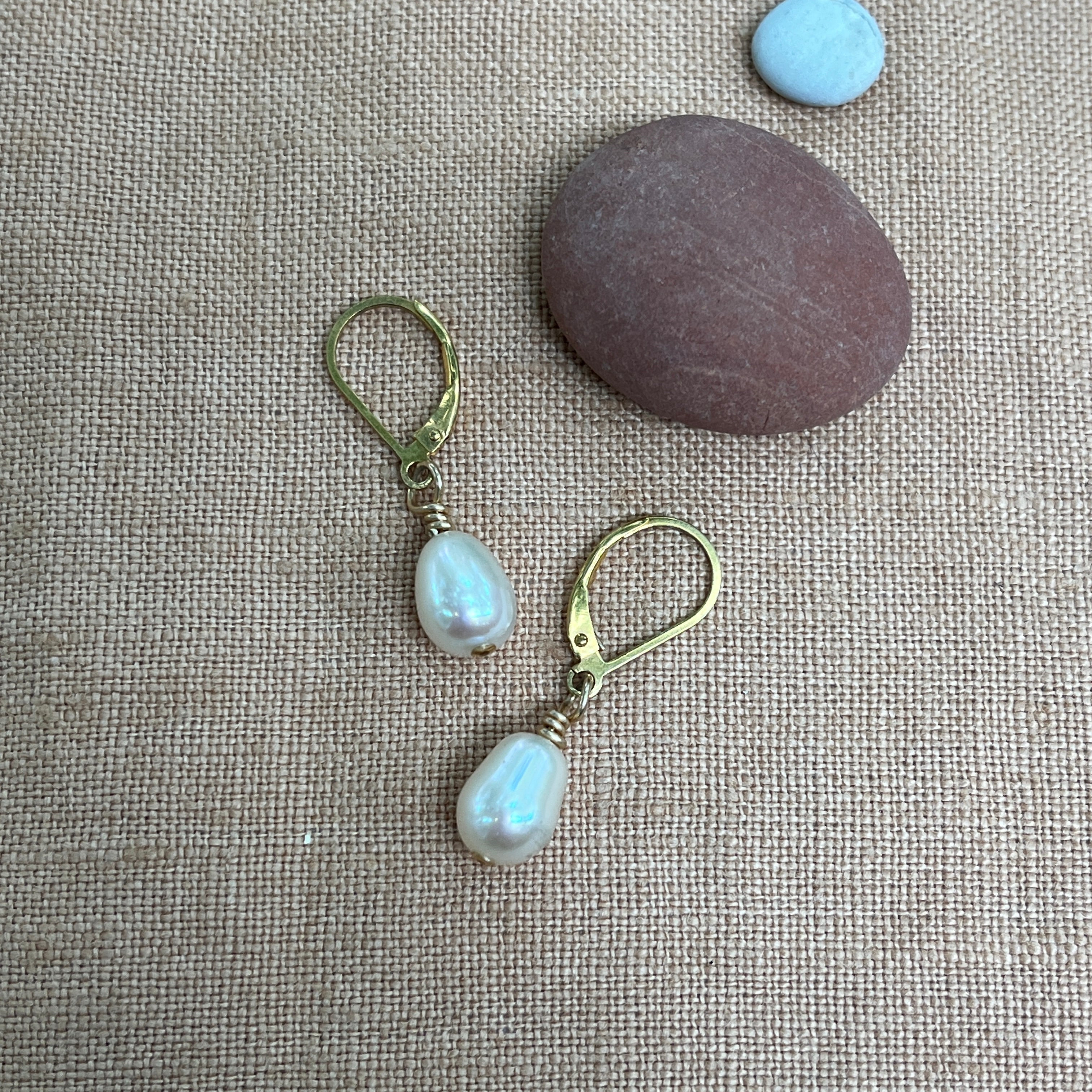 Pair of pearl earrings on a textured fabric background