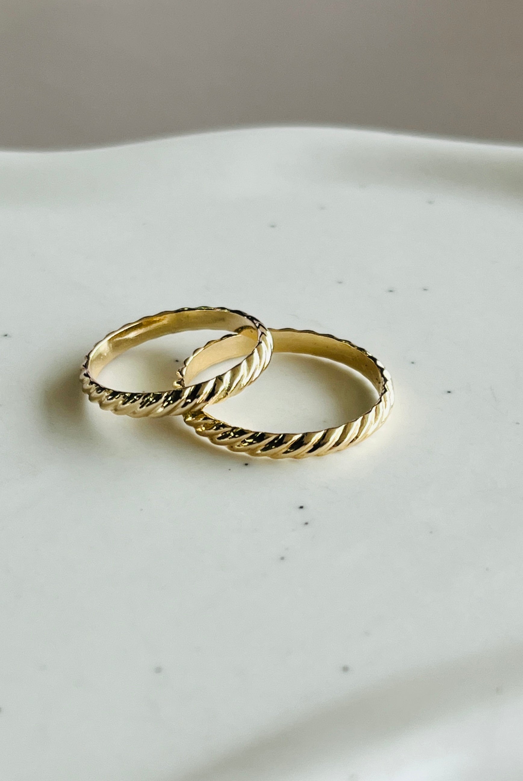 a couple of gold rings sitting on top of a white plate