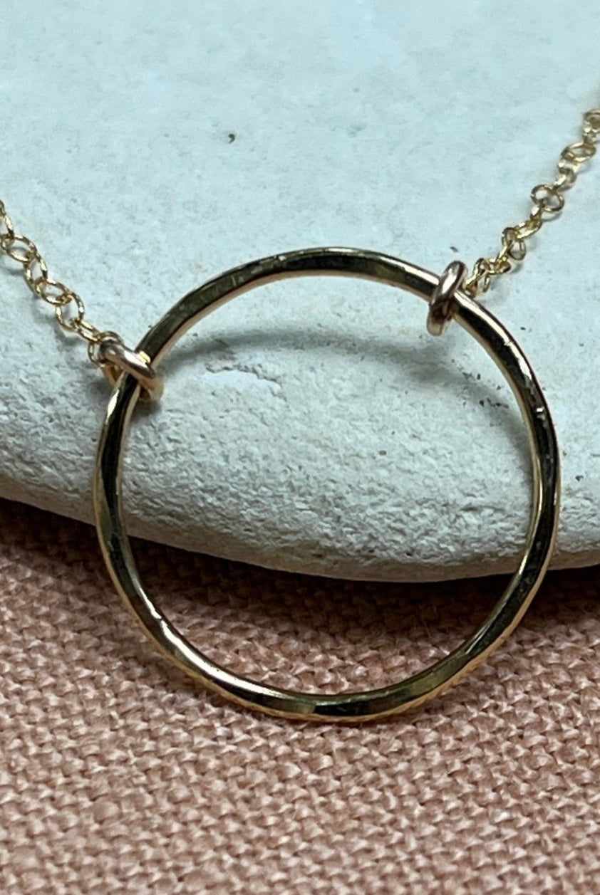 Gold necklace with interlocking rings on a light blue stone