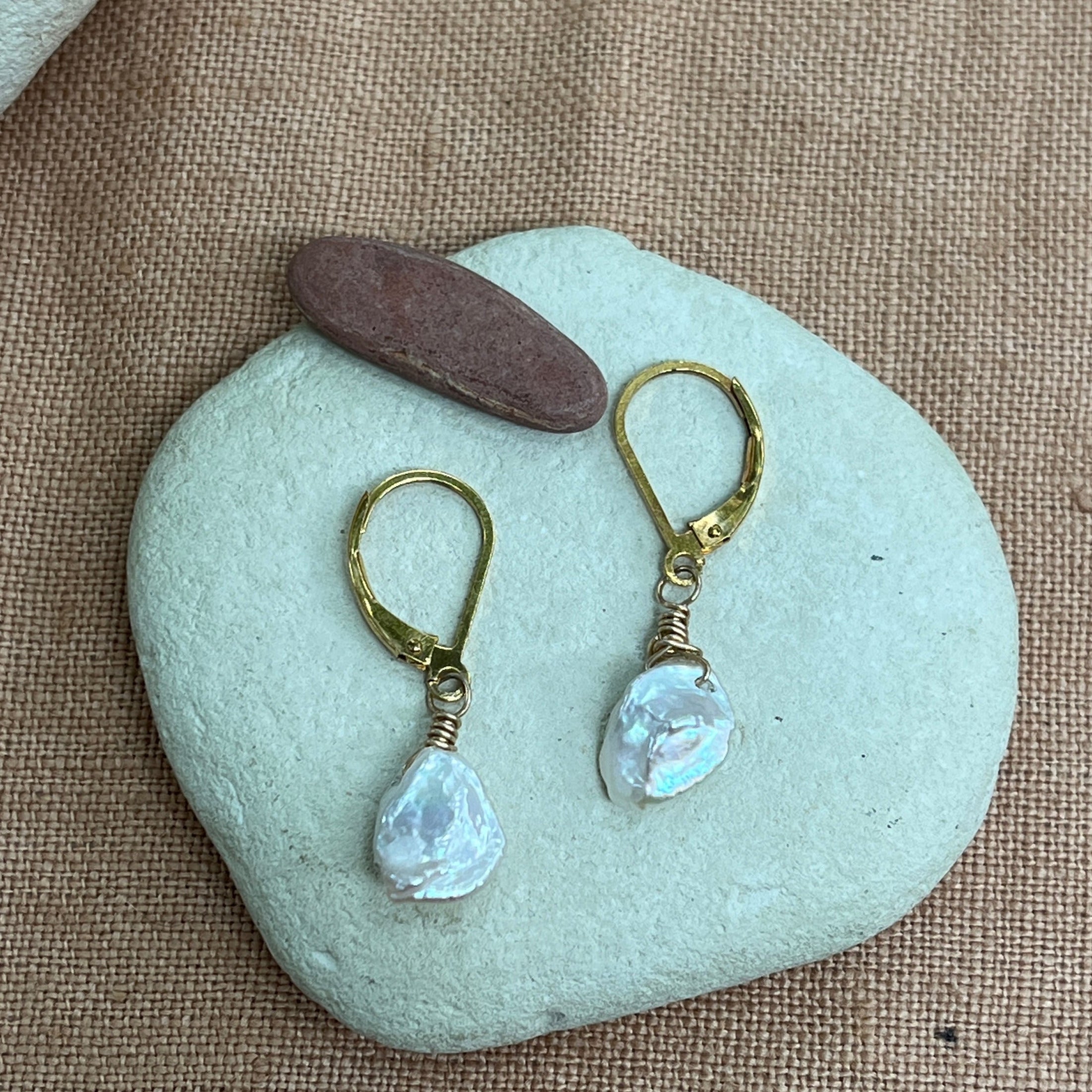 Pair of pearl earrings on a light blue stone with a natural background