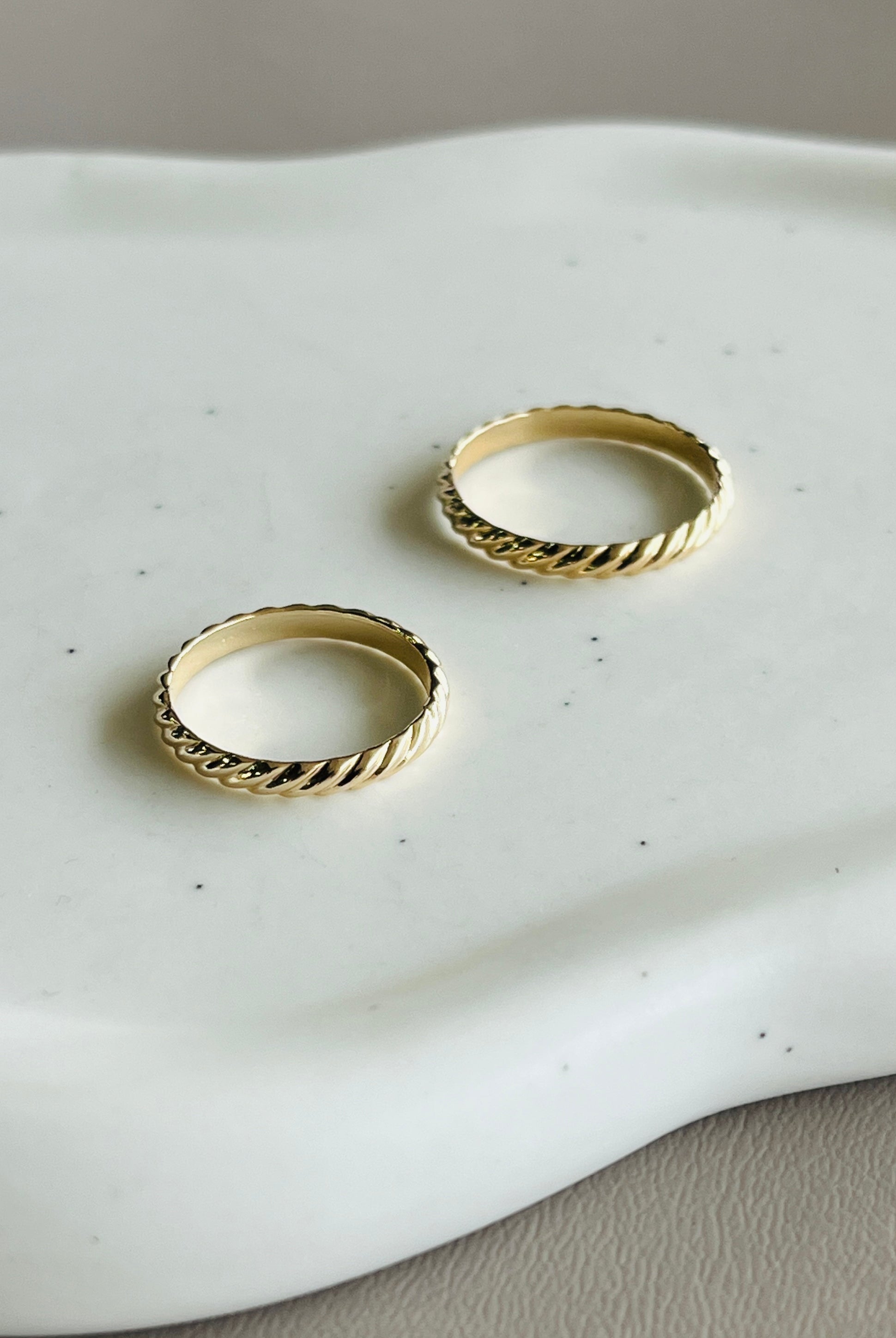 two gold rings sitting on top of a white plate