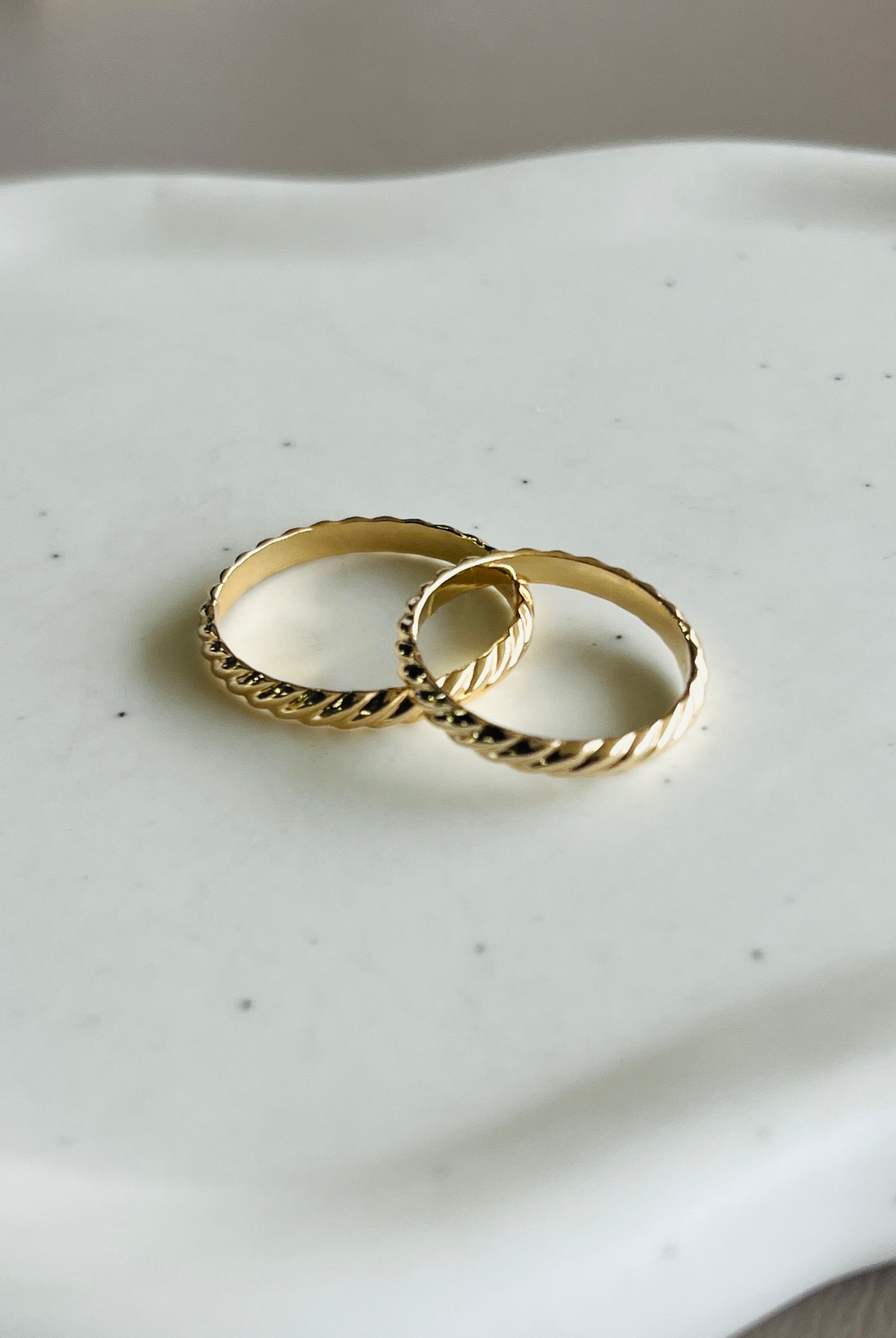 two gold wedding rings sitting on a white tray