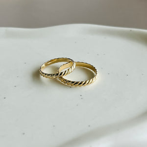 a couple of gold rings sitting on top of a white plate