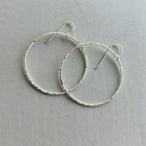 a pair of silver hoop earrings sitting on top of a table