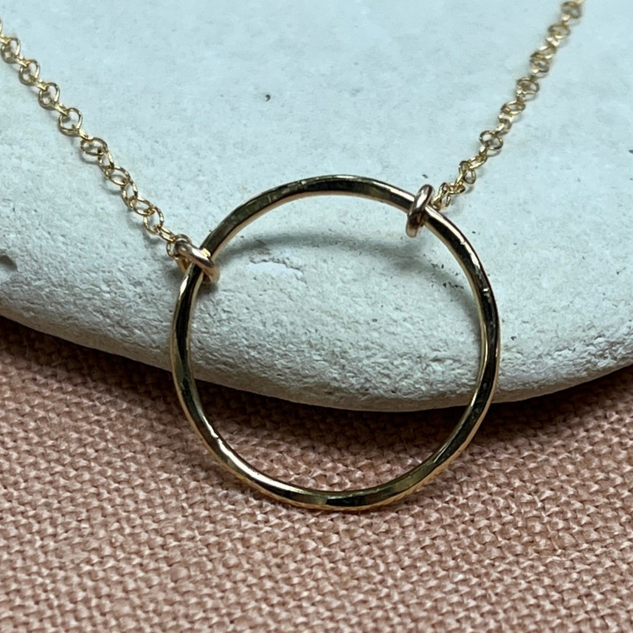 Gold necklace with interlocking rings on a light blue stone