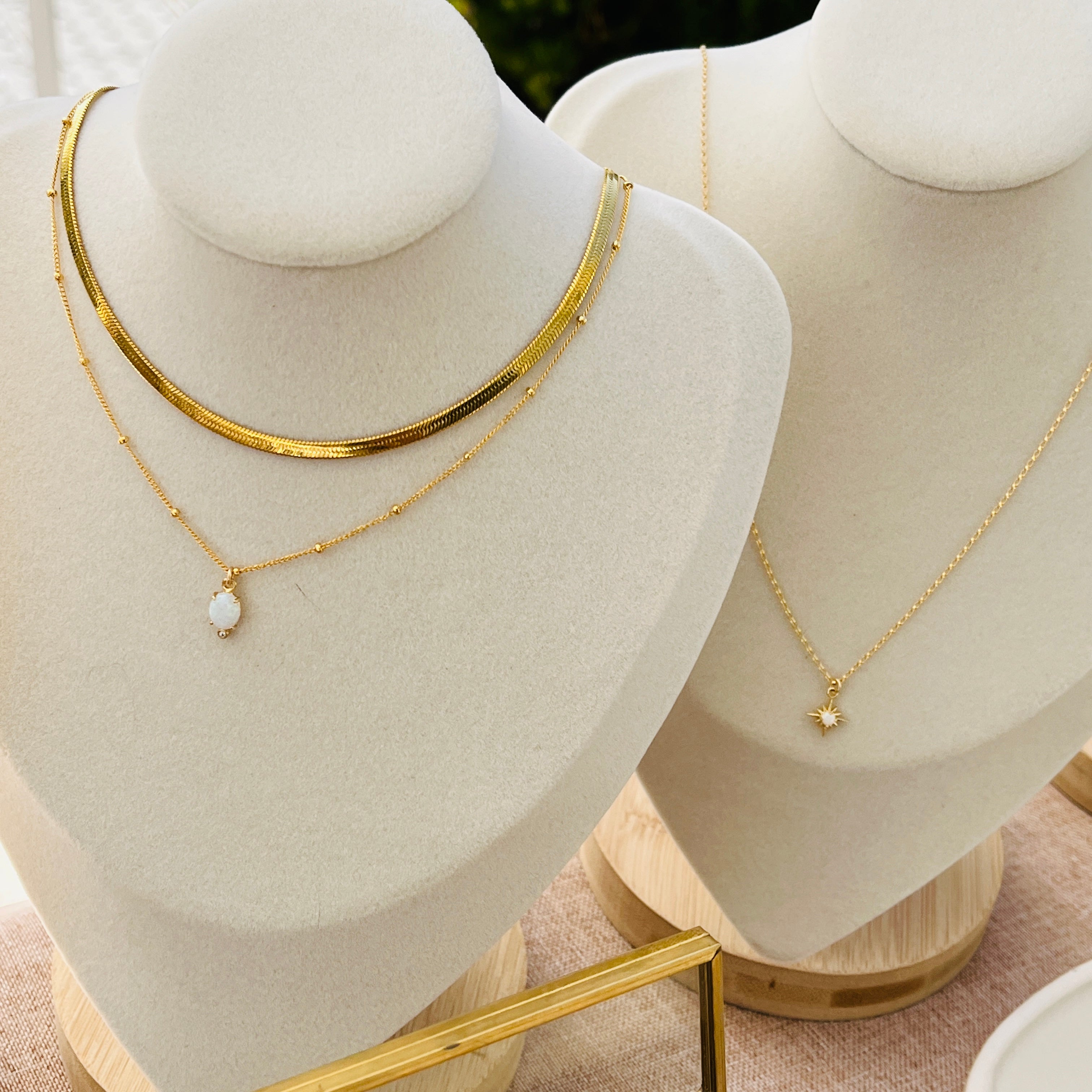 two white mannequins with gold necklaces on them