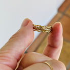 Hand holding a gold bracelet with a blurred background