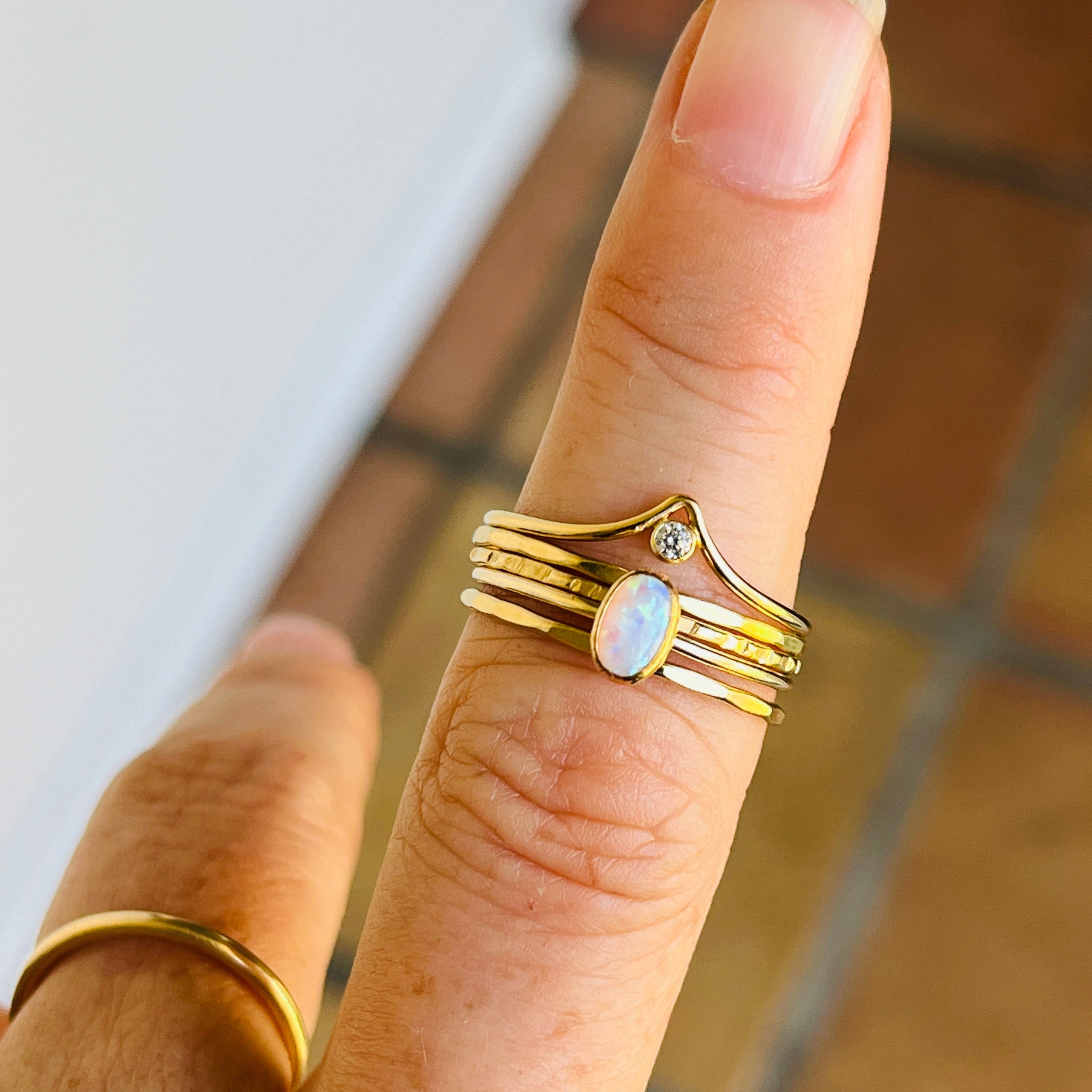 Gold ring with a central gemstone on a finger against a tiled floor background