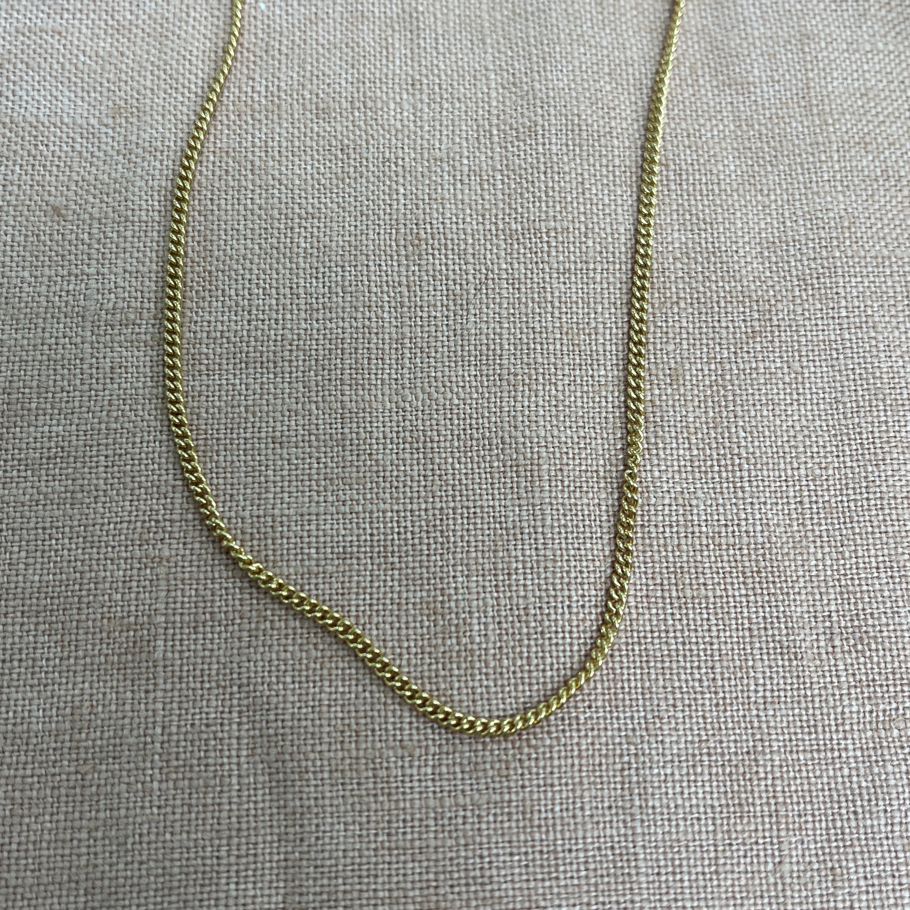 Gold chain necklace on a gray textured background