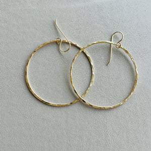 a pair of gold hoop earrings on a white surface