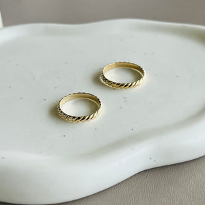 two gold rings sitting on top of a white plate