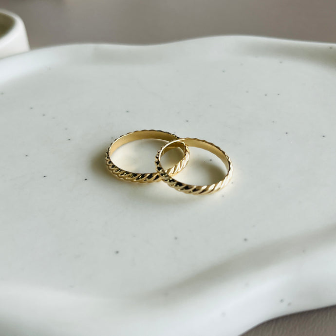 two gold wedding rings sitting on a white tray