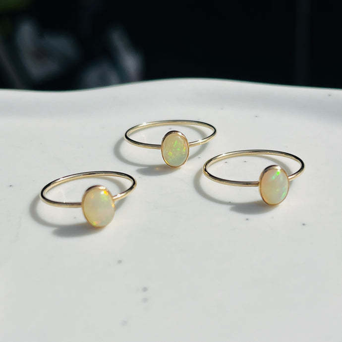 three opal rings sitting on top of a white table